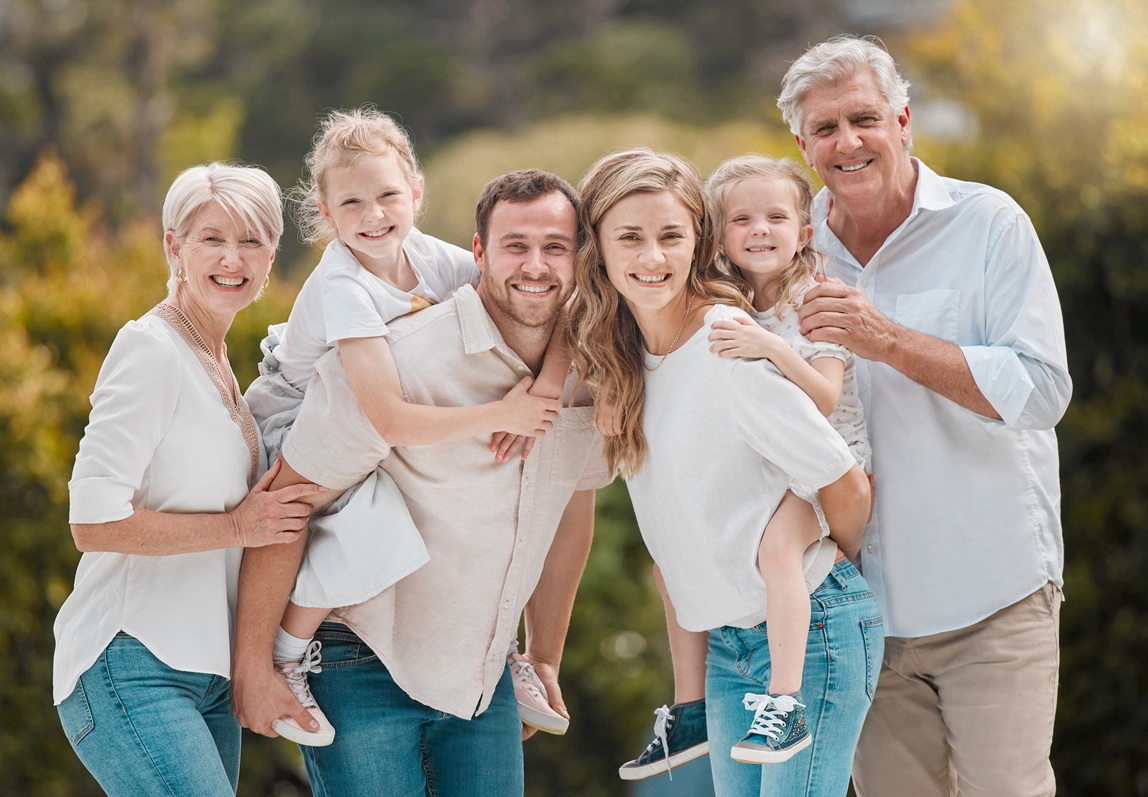 Portrait of a smiling multi generation caucasian family standing close together in the garden at ho.