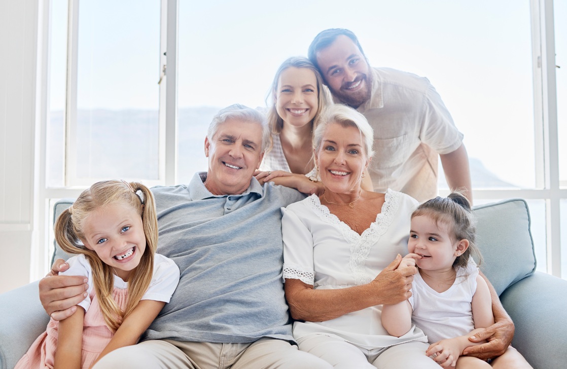 Family, love and children with a girl, parents and grandparents sitting on a living room sofa at ho.
